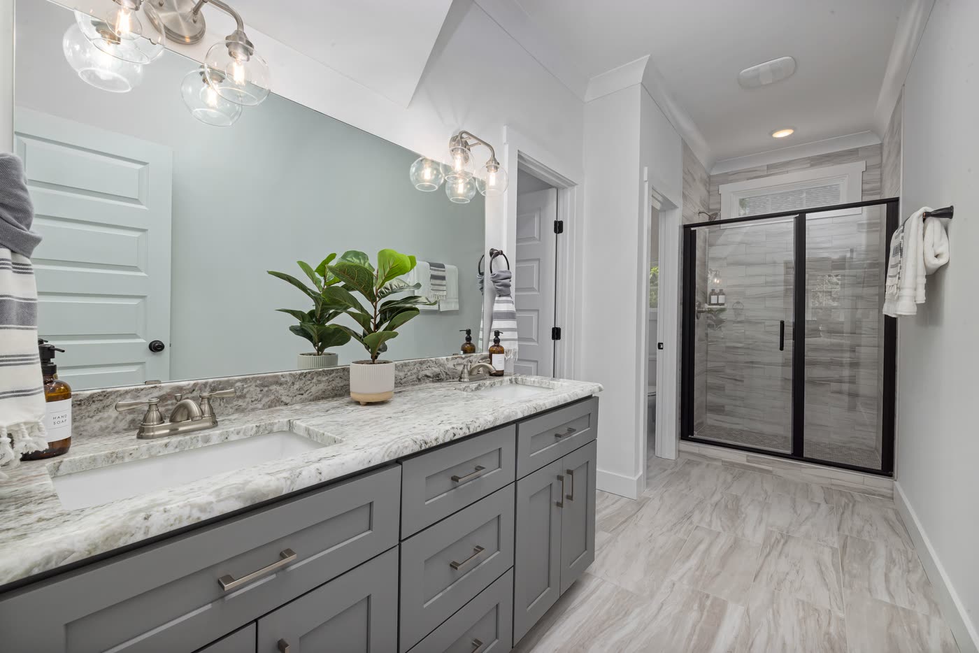 Bathroom renovation with a grey shaker double vanity, stone benchtop, sage green wall and a framed glass shower