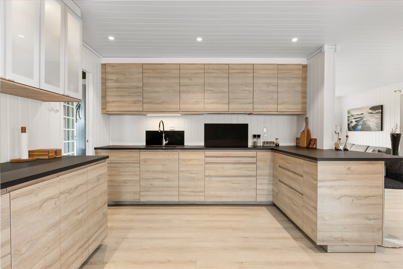 U-shaped kitchen renovation in light oak cabinetry with a dark stone benchtop and a white panelled ceiling